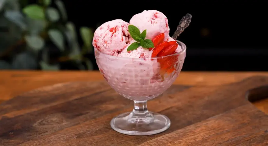 Ljuvlig jordgubbsglass utan glassmaskin i en skål, dekorerad med färska jordgubbar och mynta. Perfekt sommardessert!