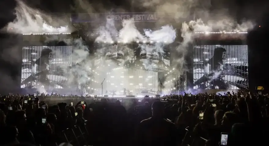 Koncert Linkin Park na Opener Festival. Tłum ludzi z telefonami, dym i światła na scenie.