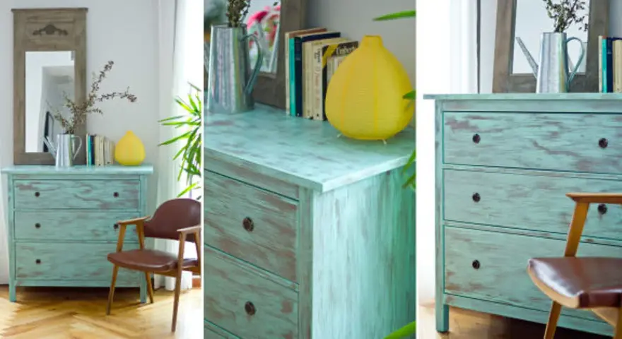Cómoda de madera con acabado desgastado, técnica de envejecer muebles de madera, junto a una silla de cuero y un espejo.