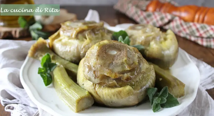 Carciofi alla romana cotti a puntino, teneri e saporiti, guarniti con menta fresca su un piatto bianco.