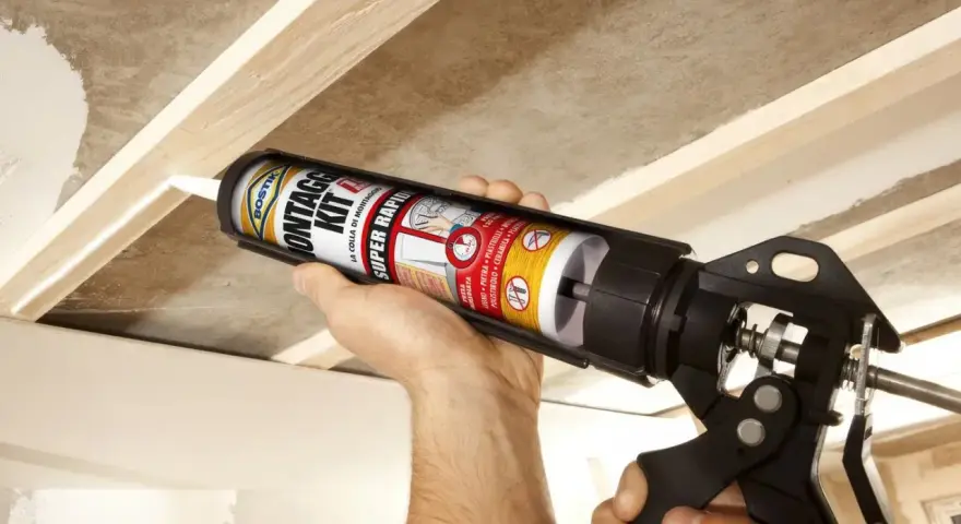 Uso di una pistola per colla per fissare il cartongesso a una struttura in legno.
