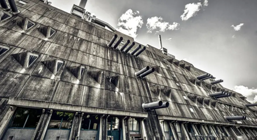 Betonriese im **Brutalismus Berlin**: Eine Fassade mit dreieckigen Fenstern und Rohren, die wie Kanonen aussehen.