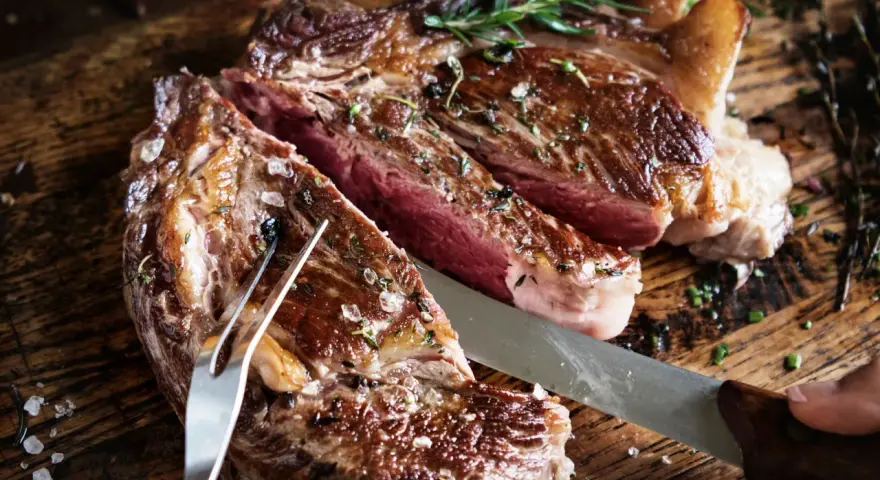 Una succulenta bistecca di manzo, tagliata al sangue, condita con sale grosso e rosmarino, pronta per essere gustata.