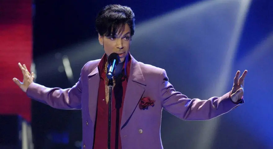 Prince w fioletowej marynarce śpiewa na scenie. Jego śmierć była szokiem dla fanów.
