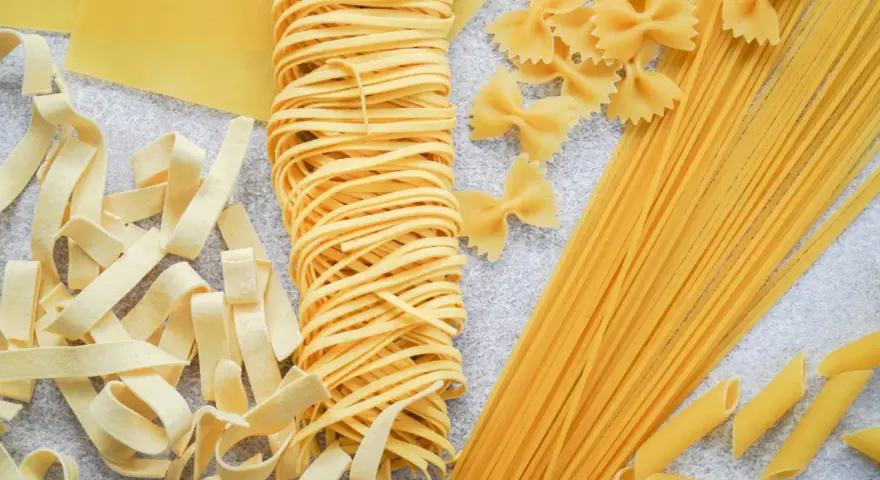 Różne rodzaje suchego makaronu: tagliatelle, farfalle, spaghetti, penne i płaty lasagne. Zastanawiasz się, ile waży makaron po ugotowaniu vs suchy?