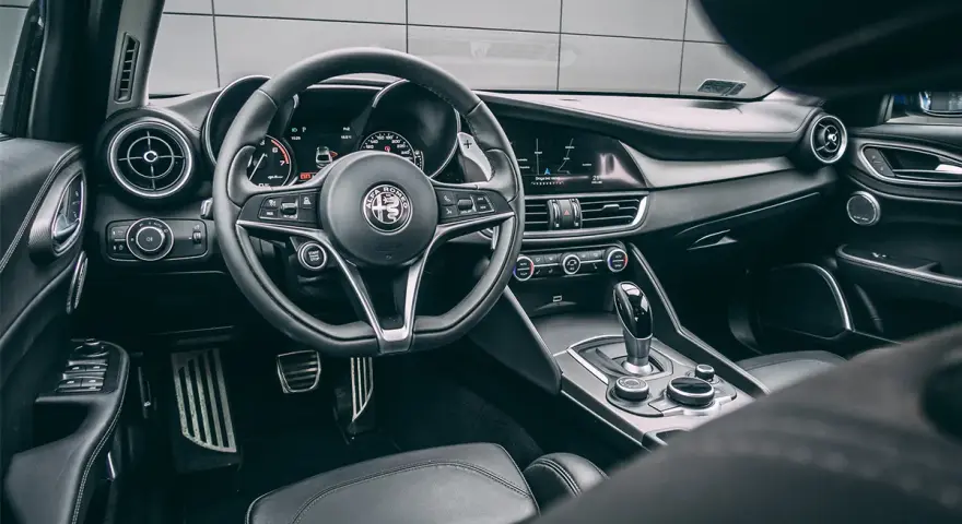 Wnętrze luksusowego samochodu Alfa Romeo. Kierownica, deska rozdzielcza i dźwignia zmiany biegów. Ta fotografia samochodowa oddaje styl i komfort.