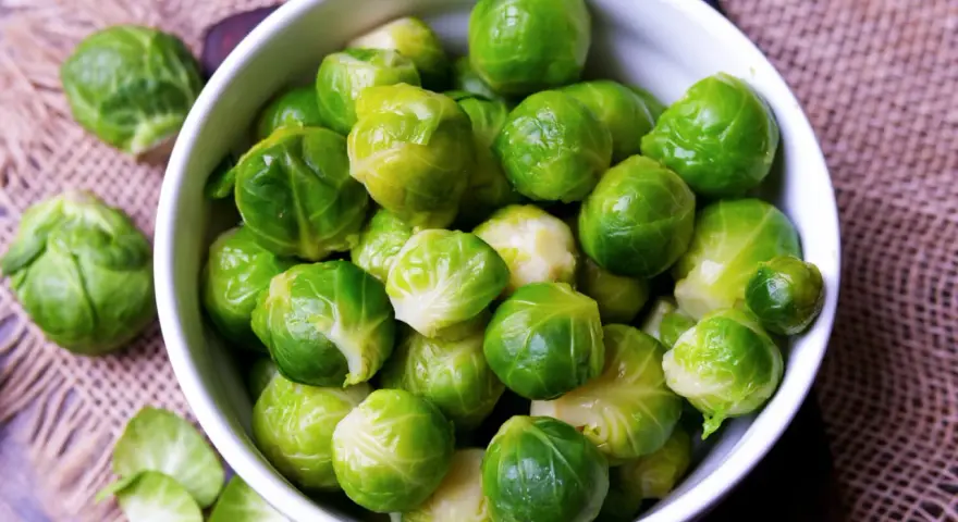 Frischer Rosenkohl in einer Schüssel. Die Frage "wie lange muss rosenkohl kochen" beschäftigt viele Hobbyköche.