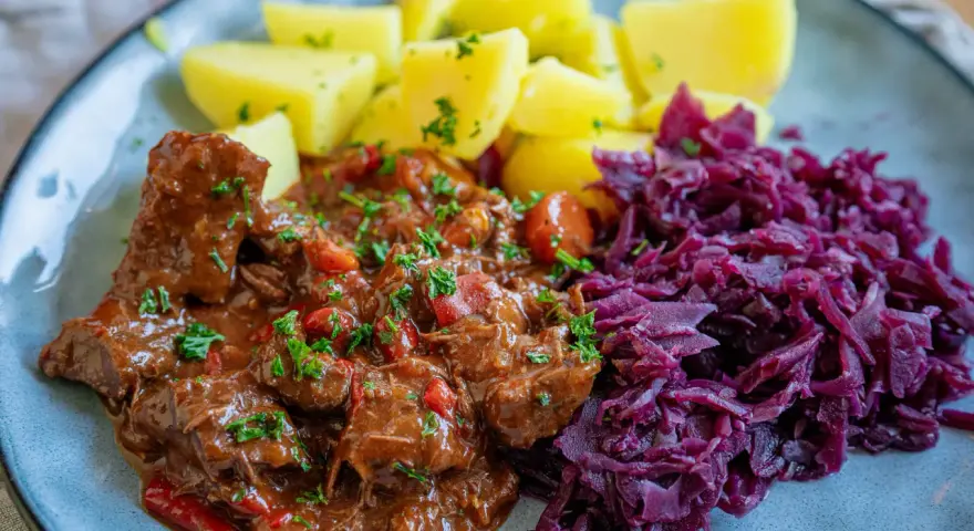 Herzhaftes Gulasch mit Kartoffeln und Rotkohl, ein klassisches Gulasch Rezept, das Leib und Seele wärmt.