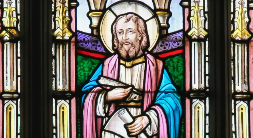Witraż przedstawia świętego Łukasza z księgą i zwojem, symbolizując jego rolę jako ewangelisty i pisarza.