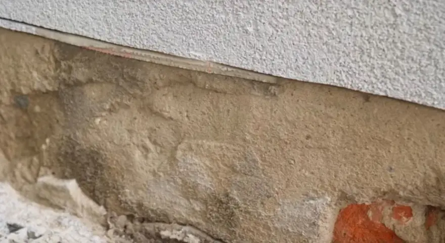 Fragment ściany z widoczną warstwą izolacji i miejscem na iniekcję.