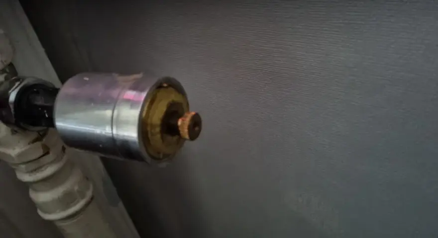 En gammal AGA termostat på ett element. Den kromade delen har en mässingsfärgad ratt.
