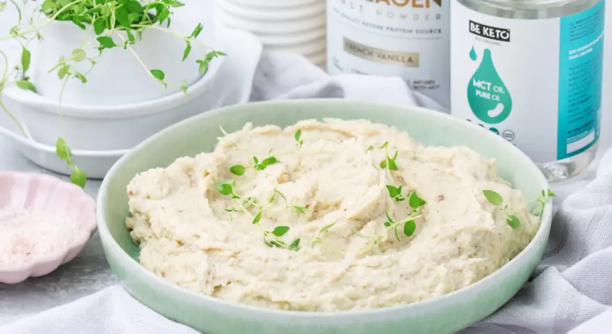 Kremowe puree z kalafiora keto, udekorowane świeżym tymiankiem. Obok miseczka z różową solą i produkty Be Keto.