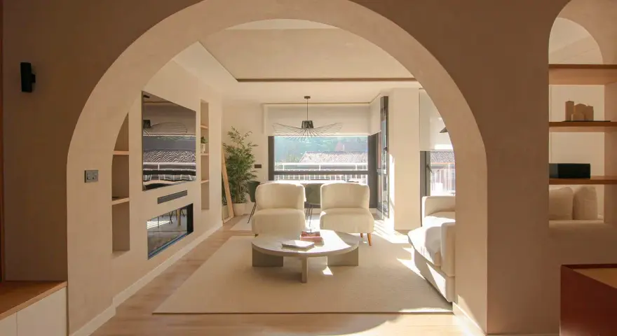 Amplio salón con entrada recibidor integrado. Dos sillones blancos, mesa de centro y sofá invitan a la relajación.