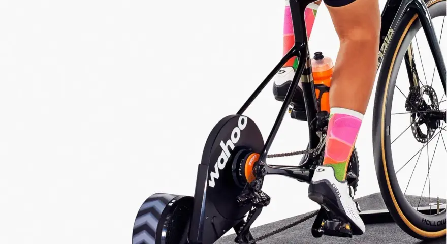 Cyclist training indoors on a bike with a Wahoo trainer, experiencing adjustable bike resistance for a challenging workout.