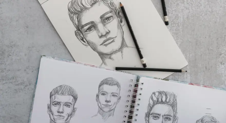 Un dégradé avec dessin de visages d'hommes au crayon. Des croquis de portraits sur un carnet ouvert, avec des crayons posés.