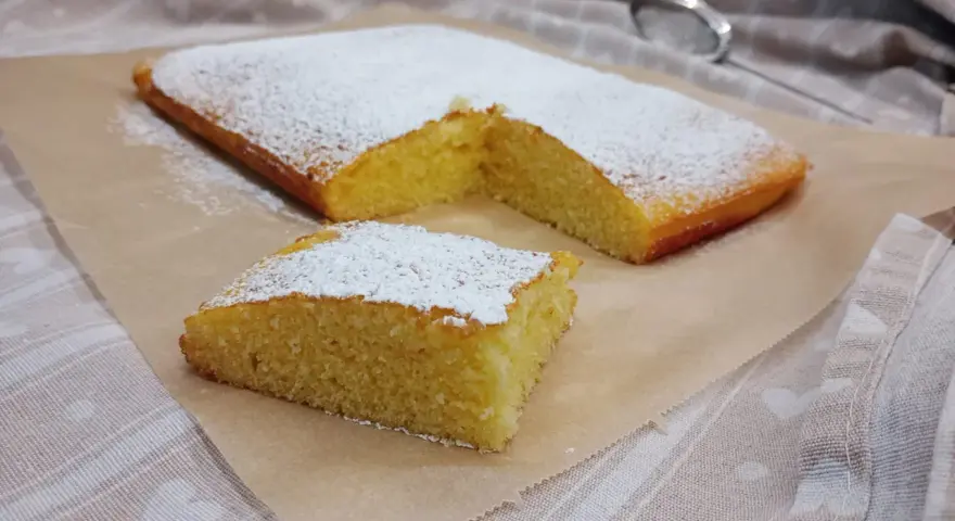 Ein saftiger Kuchen, bestäubt mit Puderzucker, ideal für glutenfreie rezepte mit reismehl.