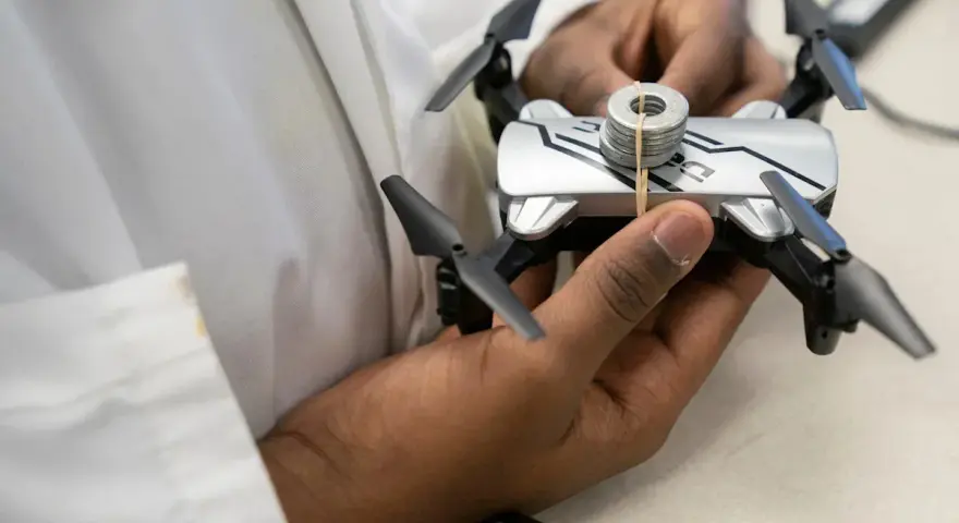 A person holds a small drone with weights attached, perhaps testing its flight capabilities in relation to Oklahoma drone laws.