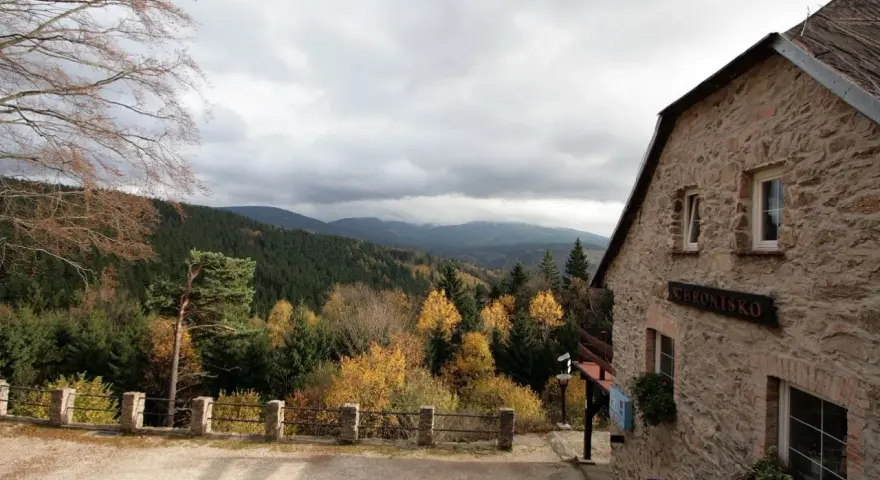 Kamienny budynek schroniska na Iglicznej z widokiem na jesienne góry.
