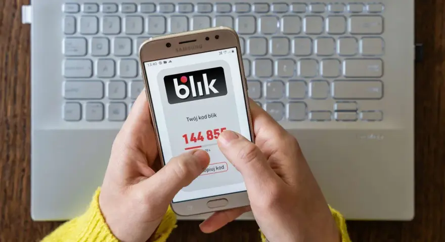 Ręce trzymają telefon z aplikacją Blik, na ekranie widoczny kod. Zastanawiasz się, jak cofnąć Blik? Ten obraz pokazuje, jak szybko uzyskać kod.