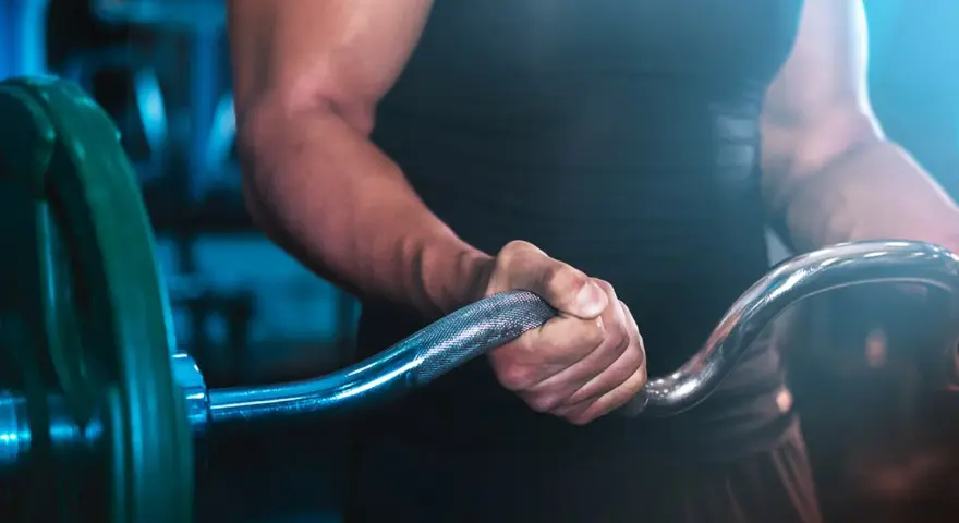Muskulös arm som greppar skivstång i ett superset gym.