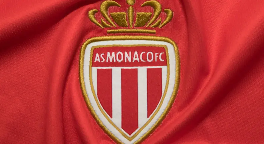 Herb AS Monaco FC na czerwonym tle. Duma z osiągnięć i rankingi klubu.