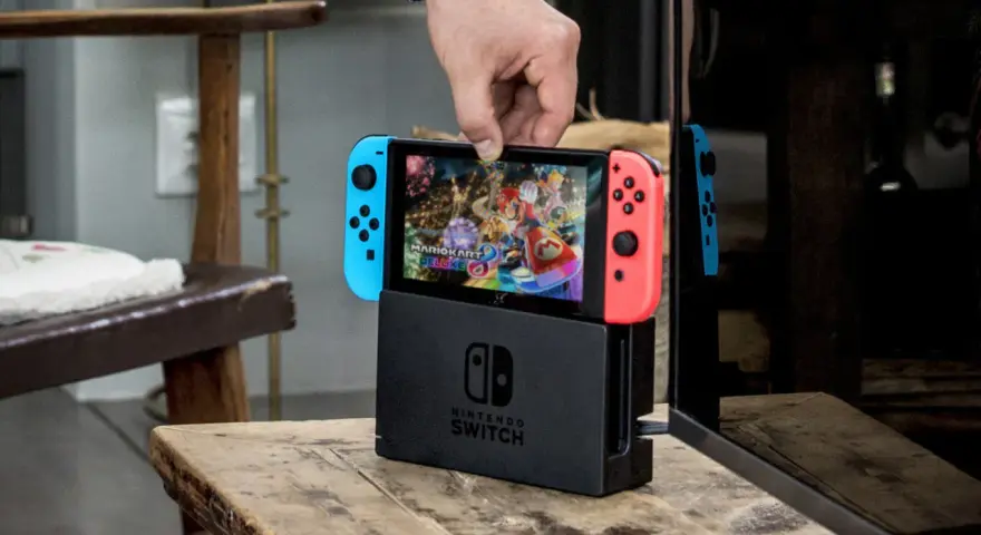 Mano insertando la Nintendo Switch en su base, lista para jugar Mario Kart 8 Deluxe, uno de los mejores juegos estrategia switch.