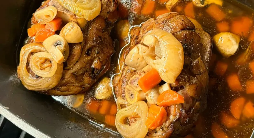 Dwie soczyste golonki, gotowane i pieczone, w aromatycznym sosie z marchewką, cebulą i grzybami. Najlepsza golonka gotowana i pieczona.