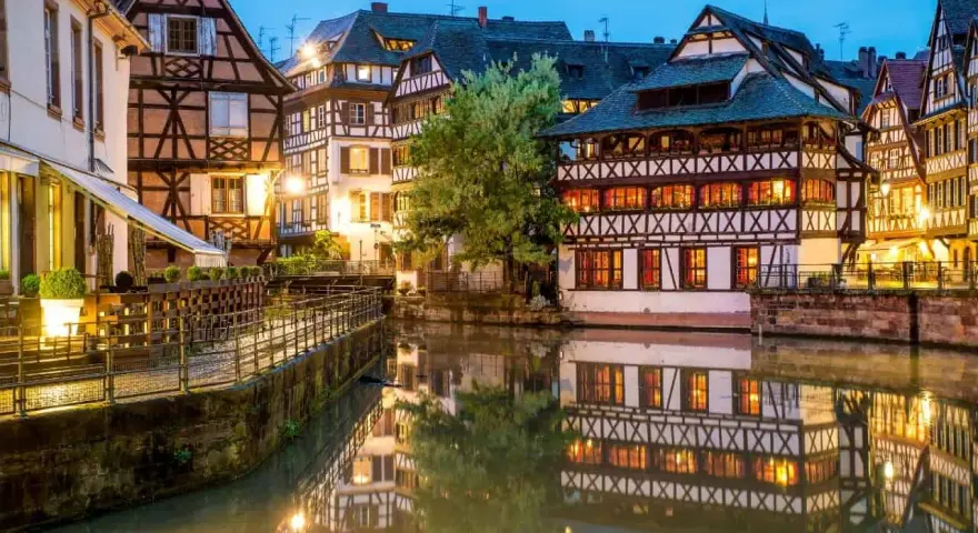 Casas con entramado de madera reflejadas en un canal, un ejemplo de la calidad de vida en Francia.
