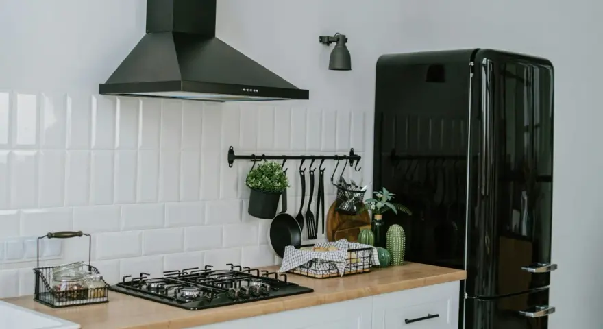 A clean vent hood filter is crucial for kitchen safety and efficiency. This image shows a modern kitchen with a black vent hood over a gas stove.