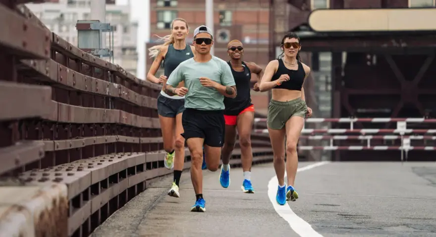 Grupa biegaczy w różnym tempie pokonuje trasę. Intensywny fartlek run na moście miejskim.