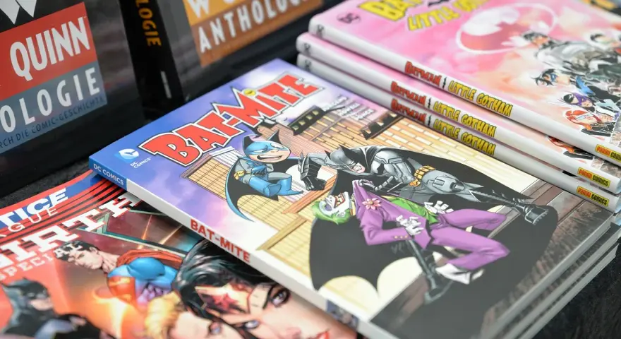 Fumetti DC Comics impilati, tra cui "Bat-Mite" e "Batman Little Gotham". Un lavoro da fumettista che prende vita.
