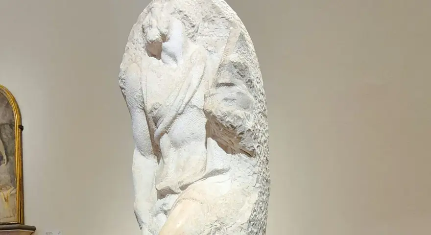 Niedokończony posąg Michała Anioła, ukazujący fragment ludzkiego ciała wyrzeźbionego z marmuru.