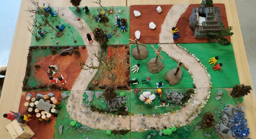 Kinder gestalten einen Kreuzweg mit Spielfiguren und Naturmaterialien. Kleine Szenen zeigen Stationen des Leidenswegs.
