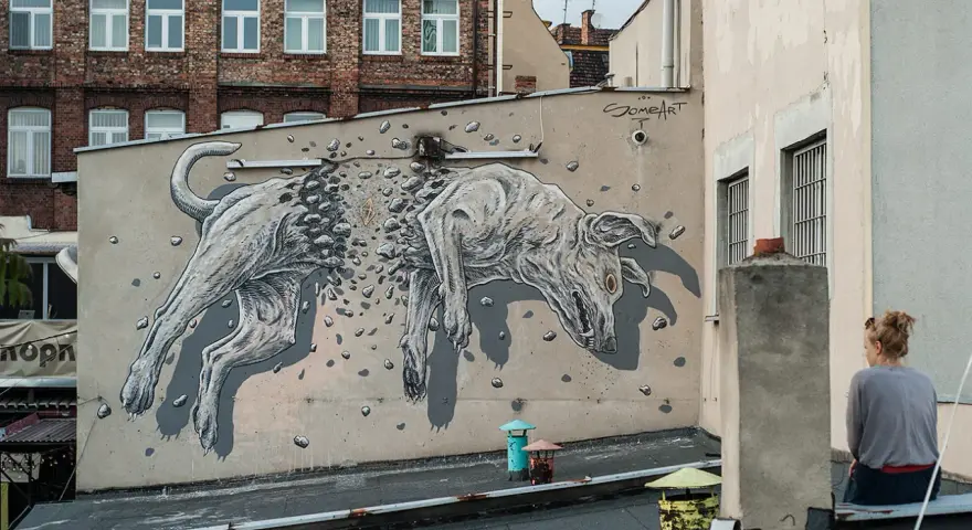 Niesamowite street art graffiti przedstawiające psa rozpadającego się na kamienie. Dzieło sztuki miejskiej na ścianie kamienicy.
