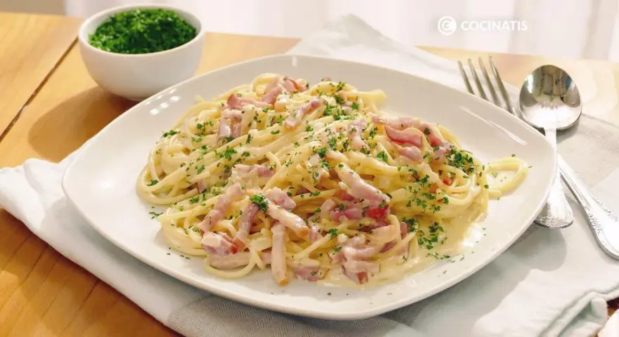 Espaguetis con nata, cubiertos de trocitos de bacon y perejil picado. Un plato cremoso y delicioso.