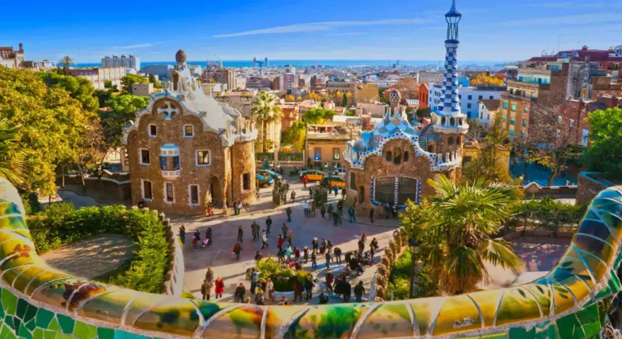 A vibrant view of Park Güell in Barcelona, with its iconic mosaic-covered benches and whimsical buildings. This is the perfect place to start your trein naar Barcelona adventure.
