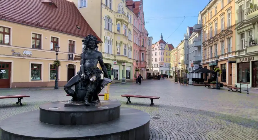 Fontanna z postacią Baccha na brukowanym placu, otoczona kolorowymi kamienicami. Zielona Góra atrakcje turystyczne.