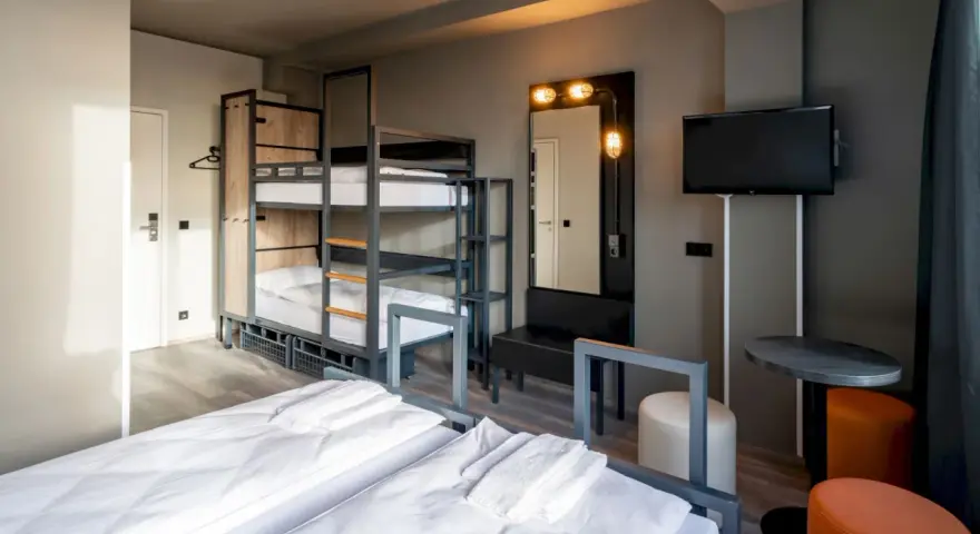 Pokój wieloosobowy w hotelu a&o Warszawa z łóżkami piętrowymi, dwoma łóżkami pojedynczymi i telewizorem.
