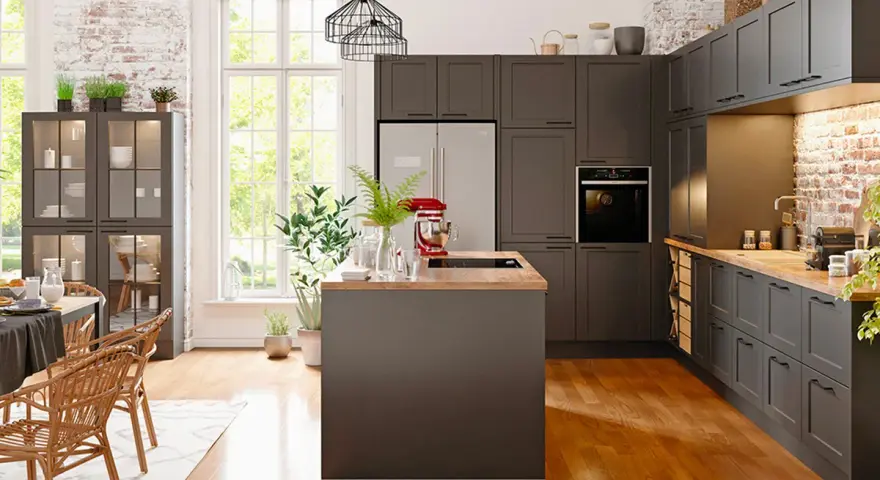 Cuisine moderne avec îlot central et armoires sombres. Un réfrigérateur non encastrable est discrètement intégré dans le décor.