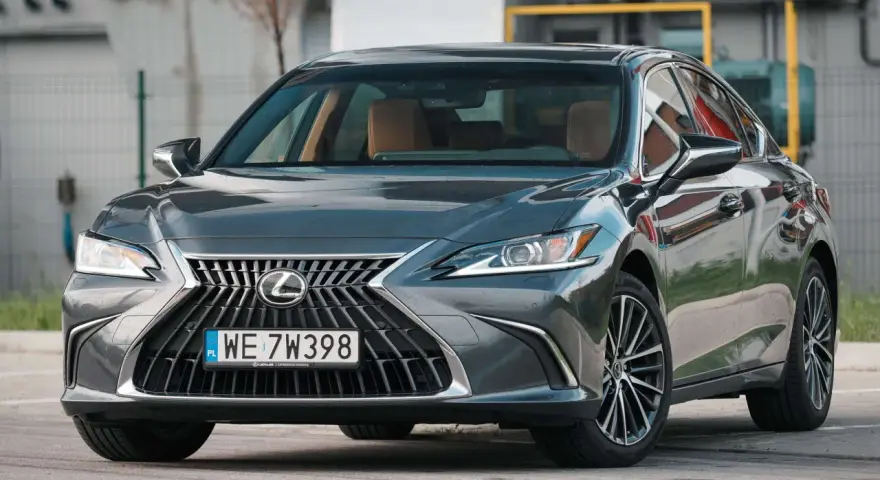 Elegancki, ciemnoszary Lexus 300h z brązowym wnętrzem stoi na parkingu.