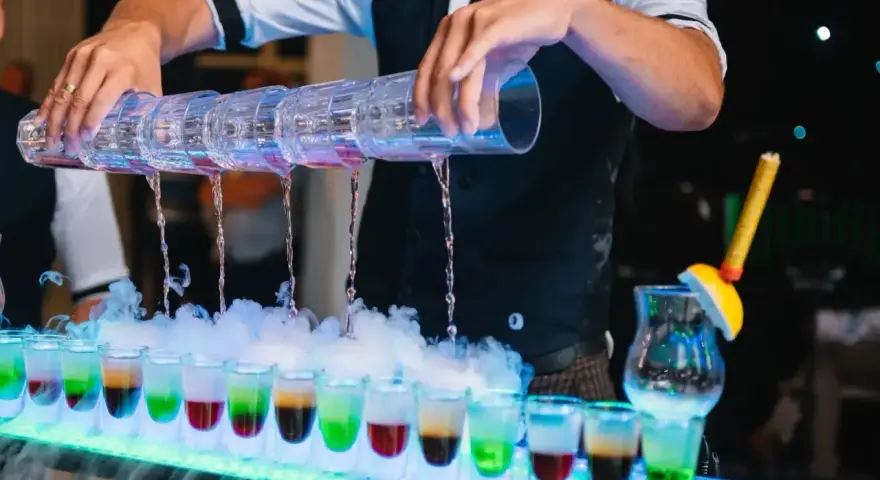 Barman nalewa kolorowe shoty na weselu. Zastanawiasz się, ile bierze barman na weselu za taką atrakcję?