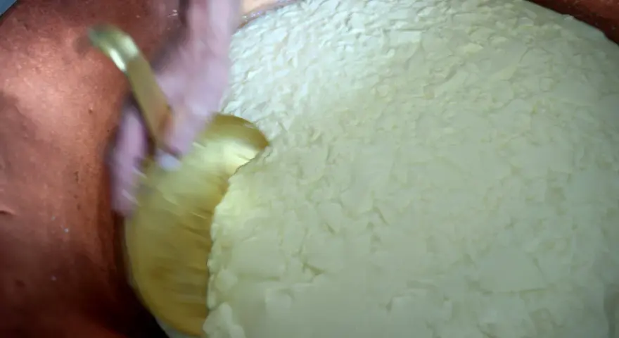 Mélange du caillé dans une cuve en cuivre, étape clé après la traite des vaches pour la fabrication du fromage.