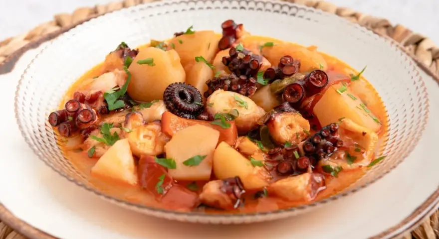 Un delicioso pulpo a la mugardesa, con patatas tiernas y un sofrito sabroso, adornado con perejil fresco.