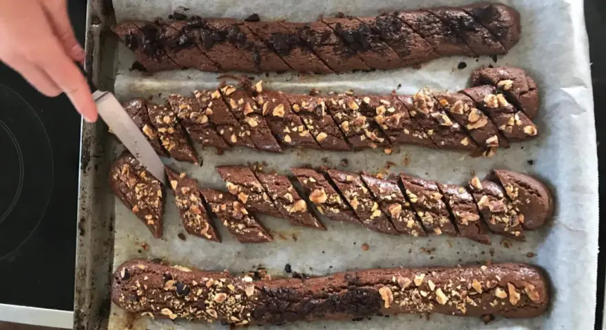 Chokladsnittar recept: Nybakade chokladkakor med nötter och chokladbitar skärs upp på en plåt.