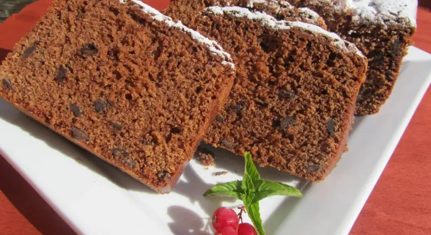 Rebanadas de bizcocho de colacao con trocitos de chocolate, espolvoreado con azúcar glas y decorado con grosellas y menta.