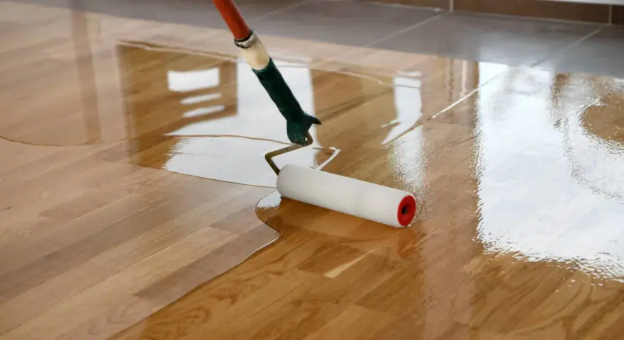 Application d'une couche de vitrificateur sur un parquet en bois. Le temps de séchage entre 2 couches est crucial pour un résultat parfait.