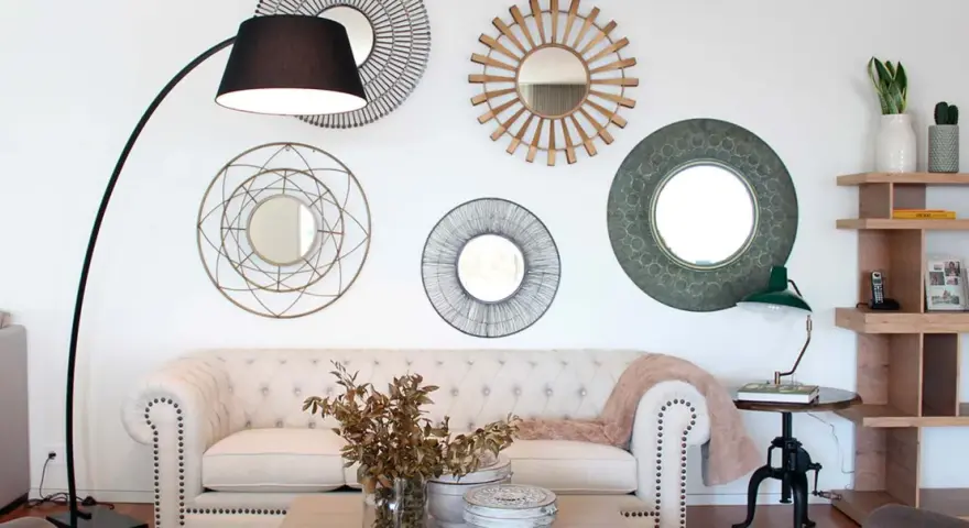 Salón moderno con sofá blanco, lámpara de pie y varios espejos decorativos que siguen principios de feng shui para atraer energía positiva.