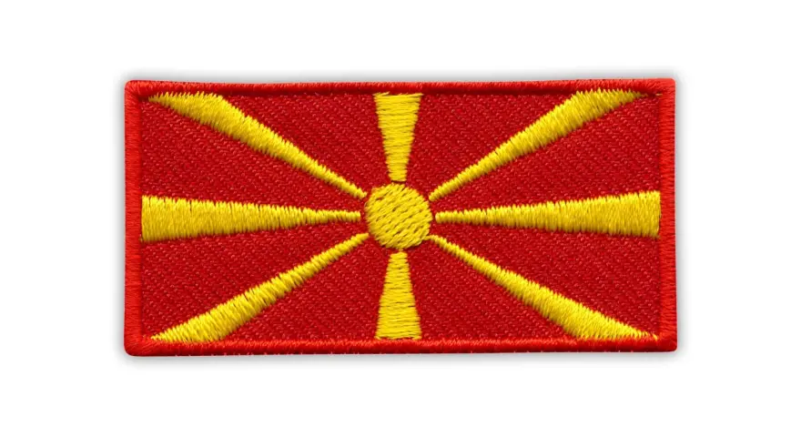 Naszywka z flagą Macedonii. Czerwone tło z żółtym słońcem i promieniami.