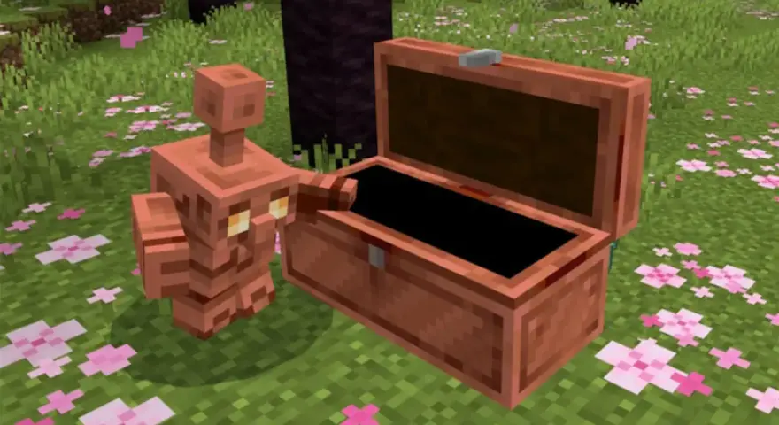 Un golem de cobre, con su cuerpo brillante, se asoma a un cofre abierto en un campo cubierto de flores rosadas.