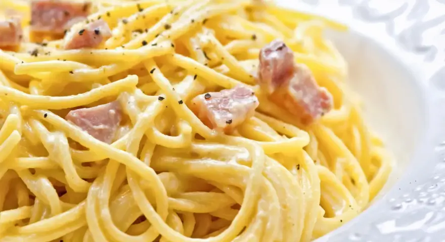 Un plato de pasta cremosa con trozos de panceta y pimienta negra molida, una auténtica carbonara original.